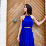 photo of beautiful young woman standing near the wooden old door in Greece