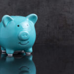 Blue shiny piggy bank on dark reflection black floor with loaft cement wall background with copy space