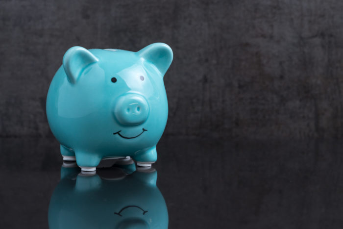 Blue shiny piggy bank on dark reflection black floor with loaft cement wall background with copy space