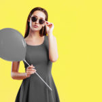 Young woman with air balloon over yellow background
